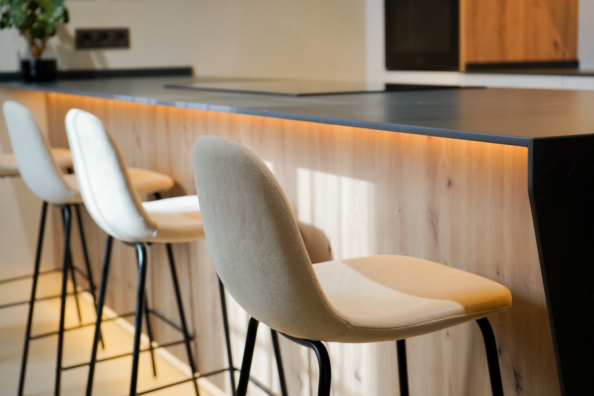 Detalle de la barra de cocina con luz integrada y taburetes tapizados