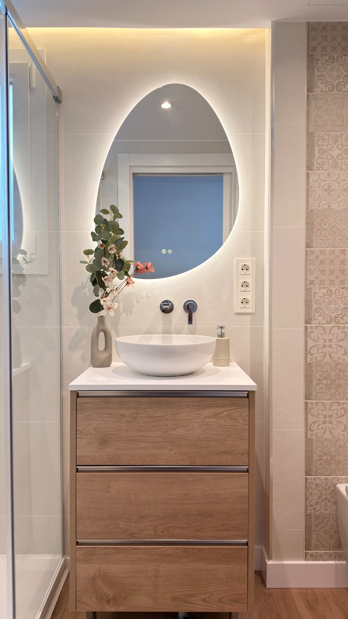 Baño de Ático Pau Casals con espejo orgánico retroiluminado y mueble suspendido