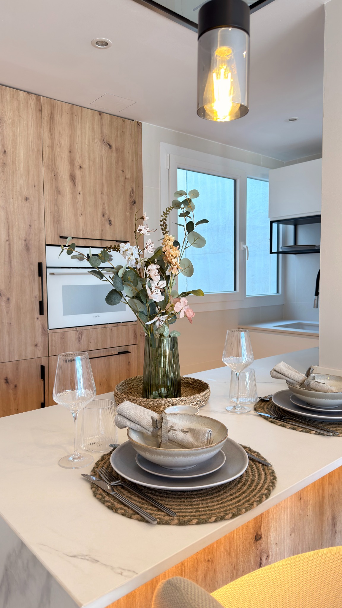 Barra de cocina con encimera clara y mobiliario acabado en madera