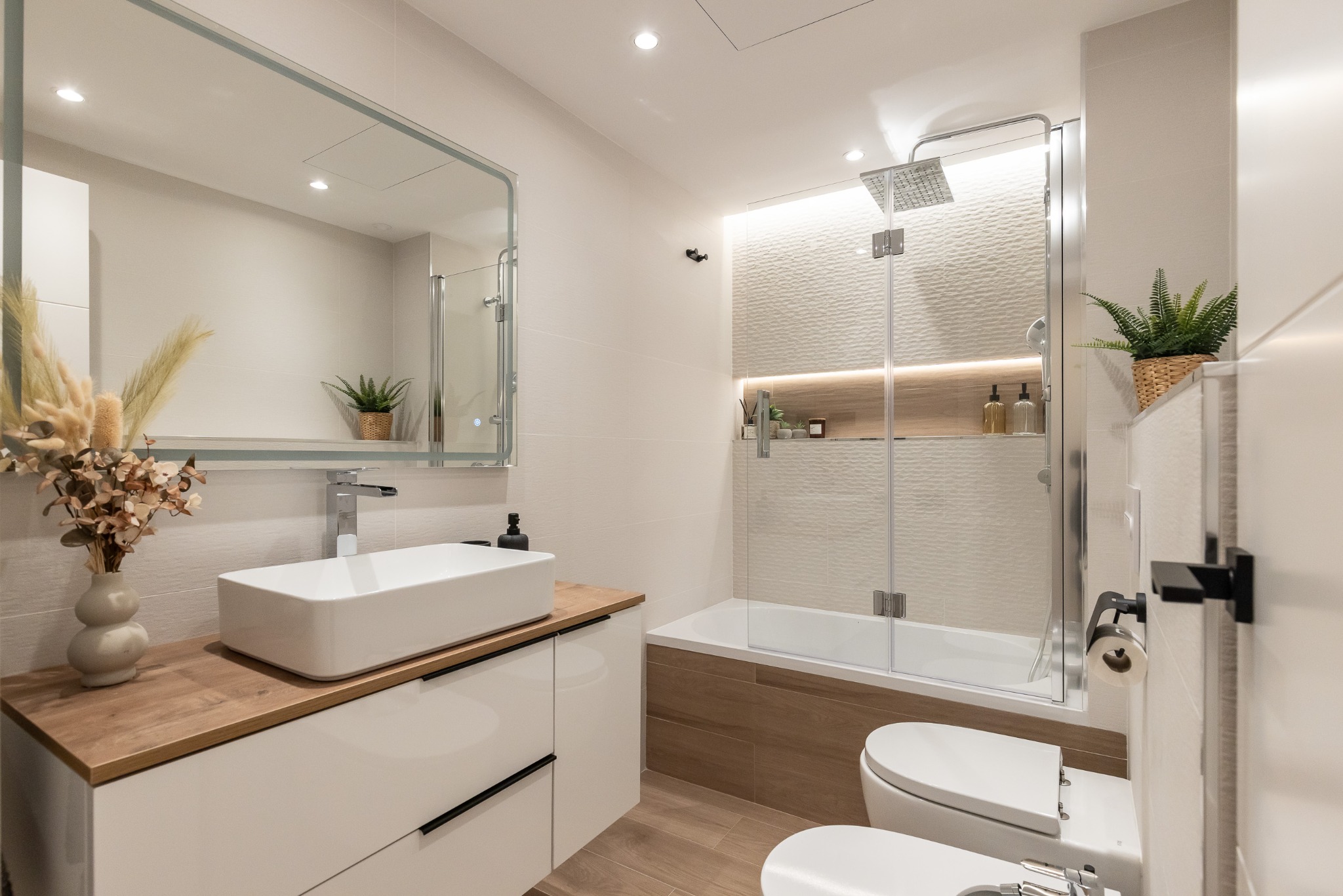 Baño renovado con bañera, lavabo sobre encimera y hornacina iluminada