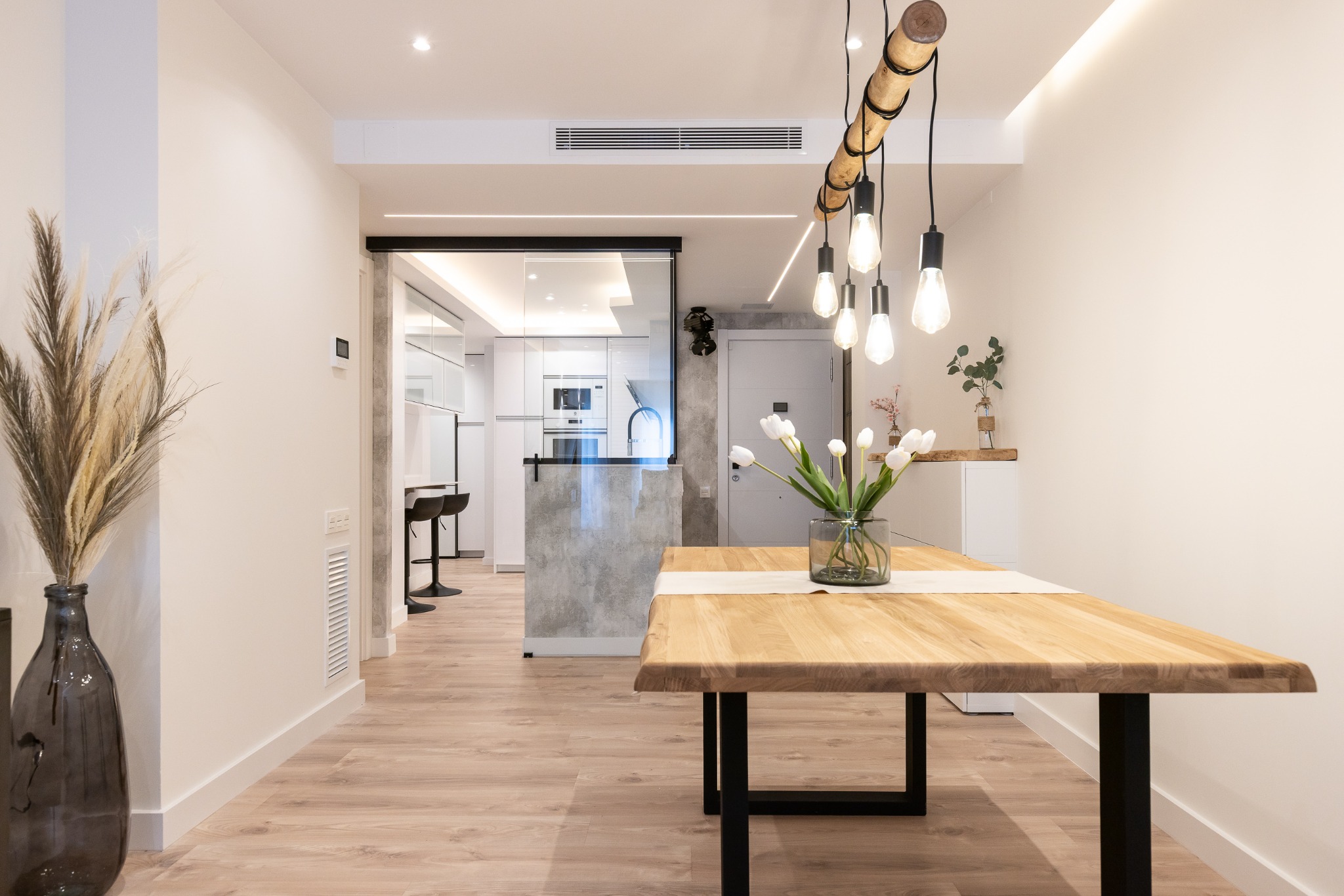 Comedor con mesa de madera y cerramiento acristalado de la cocina